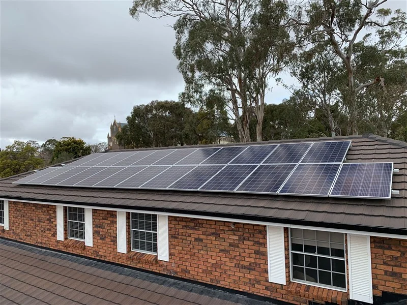 Solar panels on a brick home with gum trees