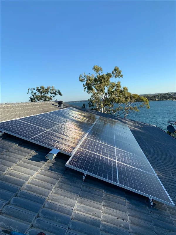 Solar panels on a tiled roof with Lake Macquarie and eucalypts behind