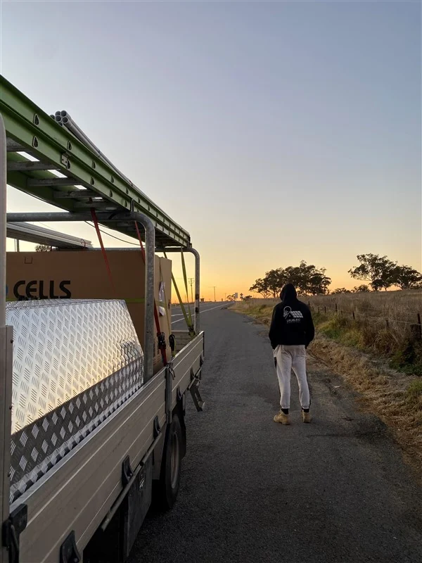 A Laurlec work ute loaded with solar panel boxes on a country road at sunset